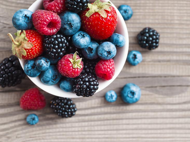 Fresh berries in a basket on rustic wooden background.